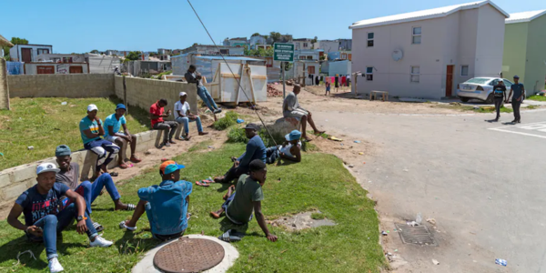 Young men waiting to be offered casual jobs in Hermanus, Western Cape, South Africa. shutterstock